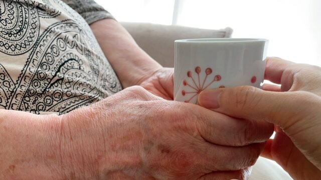 コップを持つ高齢者の手